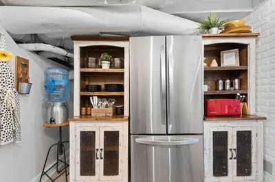 a stainless steel refrigerator in a kitchen with shelves at The Urban Roost I A Rustic City Escape in Denver