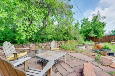 a patio with two chairs and a table and a stone wall at Less Than 1 Mi to CU Boulder Home with Fenced Yard! in Boulder