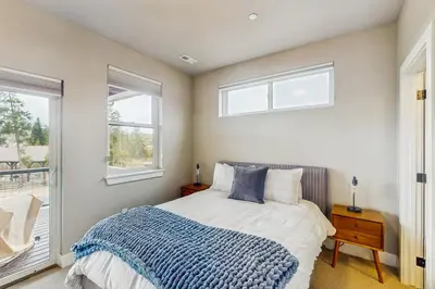 a bedroom with a bed with a blue blanket and two windows at Modern Mountain View in Fraser