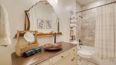 a bathroom with a sink and a mirror on a dresser at Winterhaven Estate by AvantStay Sleeps 19 Guests Mountain Compound w Views Firepit Hot Tub in Winter Park