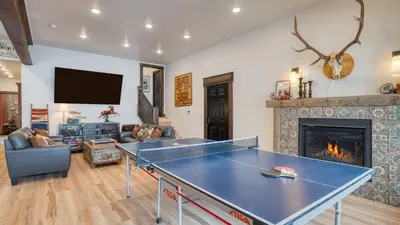 a living room with a ping pong table and a fireplace at Winterhaven Estate by AvantStay Sleeps 19 Guests Mountain Compound w Views Firepit Hot Tub in Winter Park