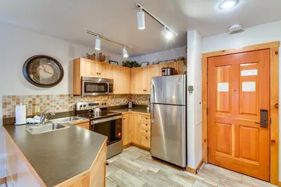 a kitchen with wooden cabinets and a stainless steel refrigerator at On-Site Gondola Access Keystone Ski Condo in Keystone
