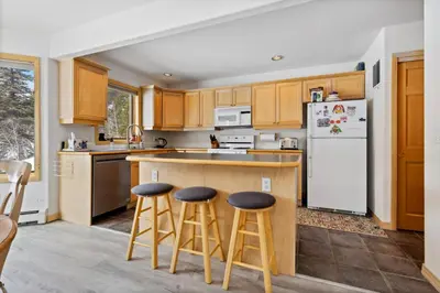 a kitchen with wooden cabinets and a white refrigerator at Charming Frisco Getaway. Close to Main St. Sleeps 8 in Frisco