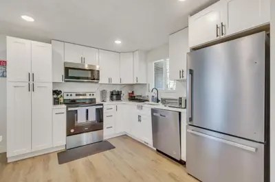 a kitchen with white cabinets and a stainless steel refrigerator at Vacation Launch Pad - Great for Groups in Arvada