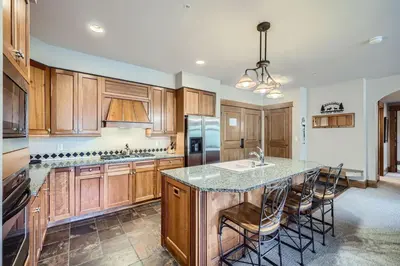 a kitchen with wooden cabinets and a island with bar stools at Lone Eagle 3013 condo in Keystone