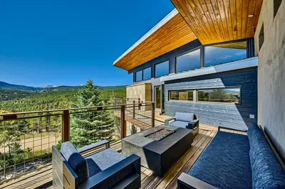 a balcony of a house with a couch and chairs at Caribou Ridge with Hot Tub! Pet Friendly with James Peak Views - Sleeps 10 in Nederland