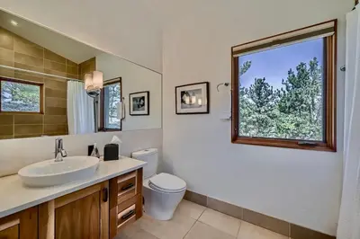 a bathroom with a sink and a toilet and a window at Caribou Ridge with Hot Tub! Pet Friendly with James Peak Views - Sleeps 10 in Nederland
