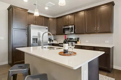 a kitchen with wooden cabinets and a counter with a wine glass at Northfield Hideaway, King Suite, EV, Pet-Friendly in Fort Collins