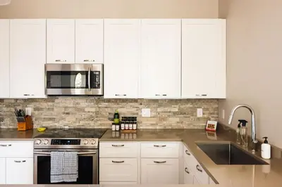 a white kitchen with white cabinets and a sink at Modern Comfort w Mountain Views - Pet-Friendly in Denver
