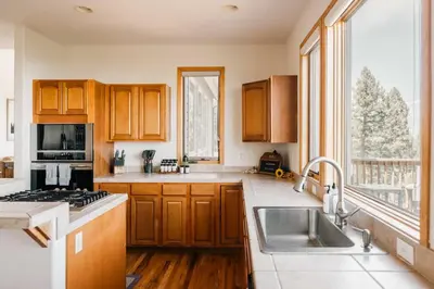 a kitchen with wooden cabinets and a large window at Peaceful Getaway with Hot Tub - Views - Evergreen in Evergreen