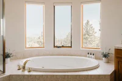 a bath tub in a bathroom with three windows at Peaceful Getaway with Hot Tub - Views - Evergreen in Evergreen