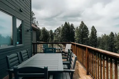 a wooden deck with a table and chairs on it at Peaceful Getaway with Hot Tub - Views - Evergreen in Evergreen