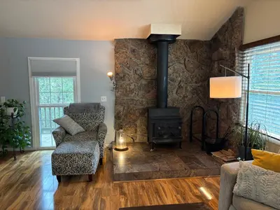 a living room with a wood stove and a chair at Peaceful in Evergreen