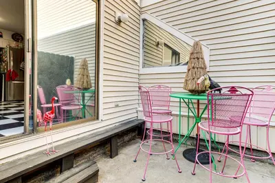 a group of pink chairs and a table on a porch at 8 Mi to Dtwn Denver Groovy Pet-Friendly Condo in Denver