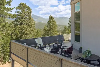 a deck with chairs and a table on a house at Summit Solace LUXE 360 Views Hot Tub Games in Bailey