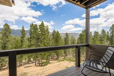 a deck with a chair and a view of the mountains at Summit Solace LUXE 360 Views Hot Tub Games in Bailey