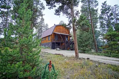a wooden house in the middle of a forest at Large Wraparound Deck, Foosball Table, Close to Beacon Landing Marina in Grand Lake