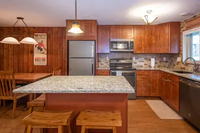 a kitchen with wooden cabinets and a kitchen island with chairs at Beaver Village 1712 - Nicely Updated, 2 Queens Plus 2 Twins, Pool, Hot Tubs, Sauna in Winter Park