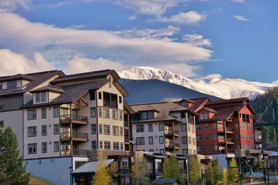 a group of buildings with a mountain in the background at Pool, Hot Tub, Ski In Ski Out, Bike Storage for Summer Guests in Winter Park