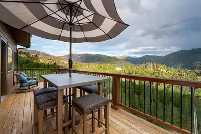 a table and chairs on a deck with an umbrella at Pool Table, Expansive Mountain Views, New Construction, Close to Town in Grand Lake