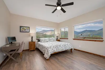 a bedroom with a bed and a desk and windows at Pool Table, Expansive Mountain Views, New Construction, Close to Town in Grand Lake