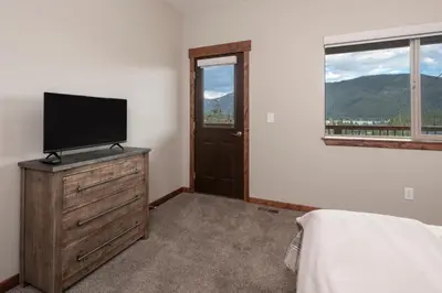a bedroom with a television on a dresser with a window at Pool Table, Expansive Mountain Views, New Construction, Close to Town in Grand Lake