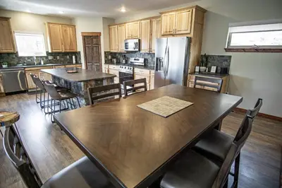 a kitchen with a wooden table and a refrigerator at Pool Table, Expansive Mountain Views, New Construction, Close to Town in Grand Lake