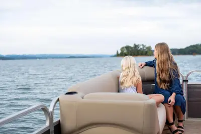 two girls sitting on a boat on the water at Great Deck with Gas Grill, Outdoor Firepit, 2 Blocks From Main Street in Grand Lake