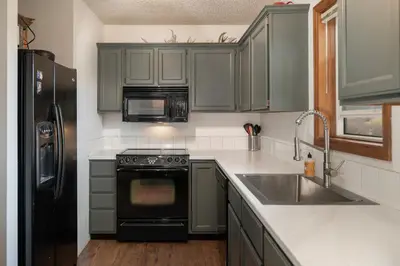 a kitchen with green cabinets and a stove and a sink at Pet Friendly - Cozy & Modern Cabin - Surrounded by Nature in Grand Lake