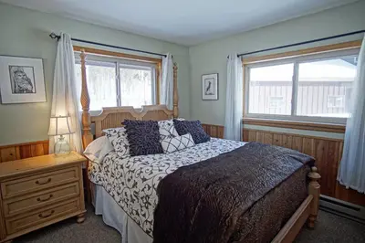 a bedroom with a bed and two windows at Pet Friendly, Firepit, Wrap around Porch, Close to Lake Granby and Highland Marina in Grand Lake