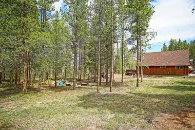 a cabin in the middle of a forest at Pet Friendly, Firepit, Wrap around Porch, Close to Lake Granby and Highland Marina in Grand Lake