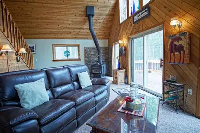a living room with a leather couch and a table at Pet Friendly, Firepit, Wrap around Porch, Close to Lake Granby and Highland Marina in Grand Lake