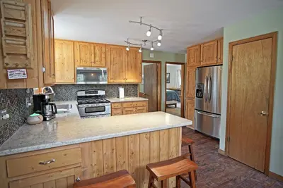 a kitchen with wooden cabinets and stainless steel appliances at Pet Friendly, Firepit, Wrap around Porch, Close to Lake Granby and Highland Marina in Grand Lake