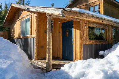a wooden cabin with a blue door in the snow at New Listing, Great Backyard with Firepit, Pet Friendly, Wood Burning Stove in Grand Lake
