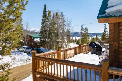 a wooden deck with snow on it at Spacious Cabin - Quality Finishes & Furniture, 2 Large Bedroom Suites Plus Den Bedroom Suite in Grand Lake