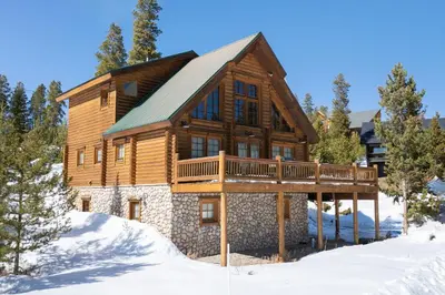 a log home with a deck in the snow at Spacious Cabin - Quality Finishes & Furniture, 2 Large Bedroom Suites Plus Den Bedroom Suite in Grand Lake