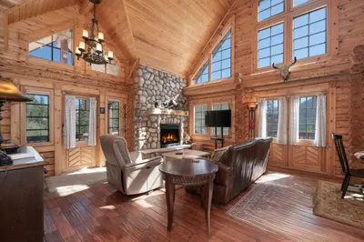 a living room with a fireplace in a log cabin at Spacious Cabin - Quality Finishes & Furniture, 2 Large Bedroom Suites Plus Den Bedroom Suite in Grand Lake