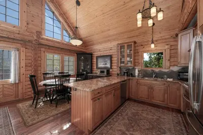 a kitchen with wooden cabinets and a table in a cabin at Spacious Cabin - Quality Finishes & Furniture, 2 Large Bedroom Suites Plus Den Bedroom Suite in Grand Lake