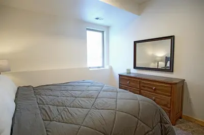 a bedroom with a bed and a mirror on a dresser at New Hot Tub, Firepit, Laundry, Big Front Deck with Great Views in Grand Lake