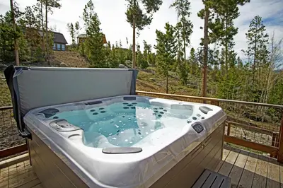 a hot tub on the deck of a house at New Hot Tub, Firepit, Laundry, Big Front Deck with Great Views in Grand Lake