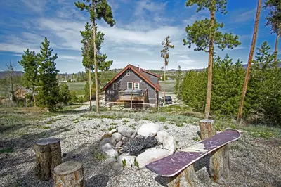 a log cabin with a skateboard in front of a campfire at New Hot Tub, Firepit, Laundry, Big Front Deck with Great Views in Grand Lake