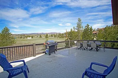 a patio with chairs and a grill on a deck at New Hot Tub, Firepit, Laundry, Big Front Deck with Great Views in Grand Lake