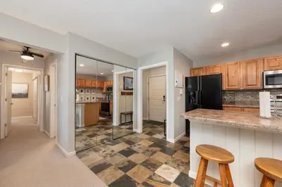 a kitchen with wooden cabinets and a checkered floor at Versatile Rental, Firepit, Balcony with Grill and Outdoor Seating in Fraser