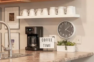 a kitchen counter with a coffee time sign and a clock at Versatile Rental, Firepit, Balcony with Grill and Outdoor Seating in Fraser