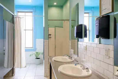 a bathroom with two sinks and a tv on the wall at Hostel Fish in Denver