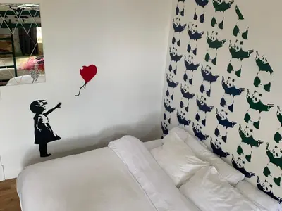 a bedroom with a bed and a wall with a woman holding a balloon at Hostel Fish in Denver
