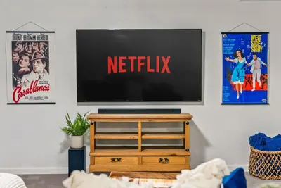 a television on a stand in a living room with posters at The Gather House Stylish Stay w Room to Play in Westminster