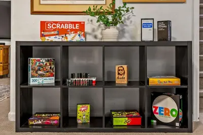 a shelf with games and other items on it at The Gather House Stylish Stay w Room to Play in Westminster