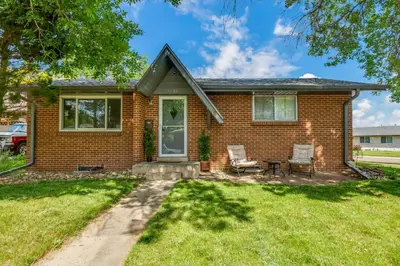 a brick house with two chairs and a table at 4BD Near DT | Hot Tub, Pingpong & Backyard Fun in Arvada