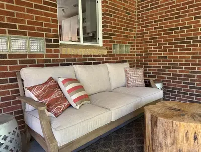 a white couch with pillows on a brick wall at Crown Hill Gem - Hot Tub, Yard, Parking in Lakewood